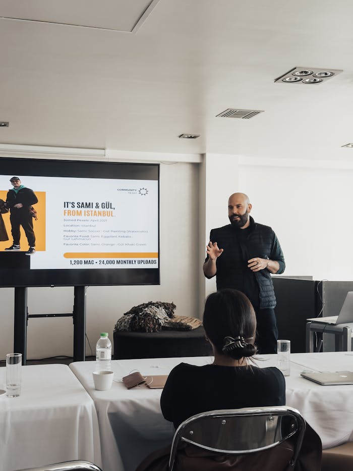 A business professional delivers a presentation to colleagues in a modern meeting room setting.