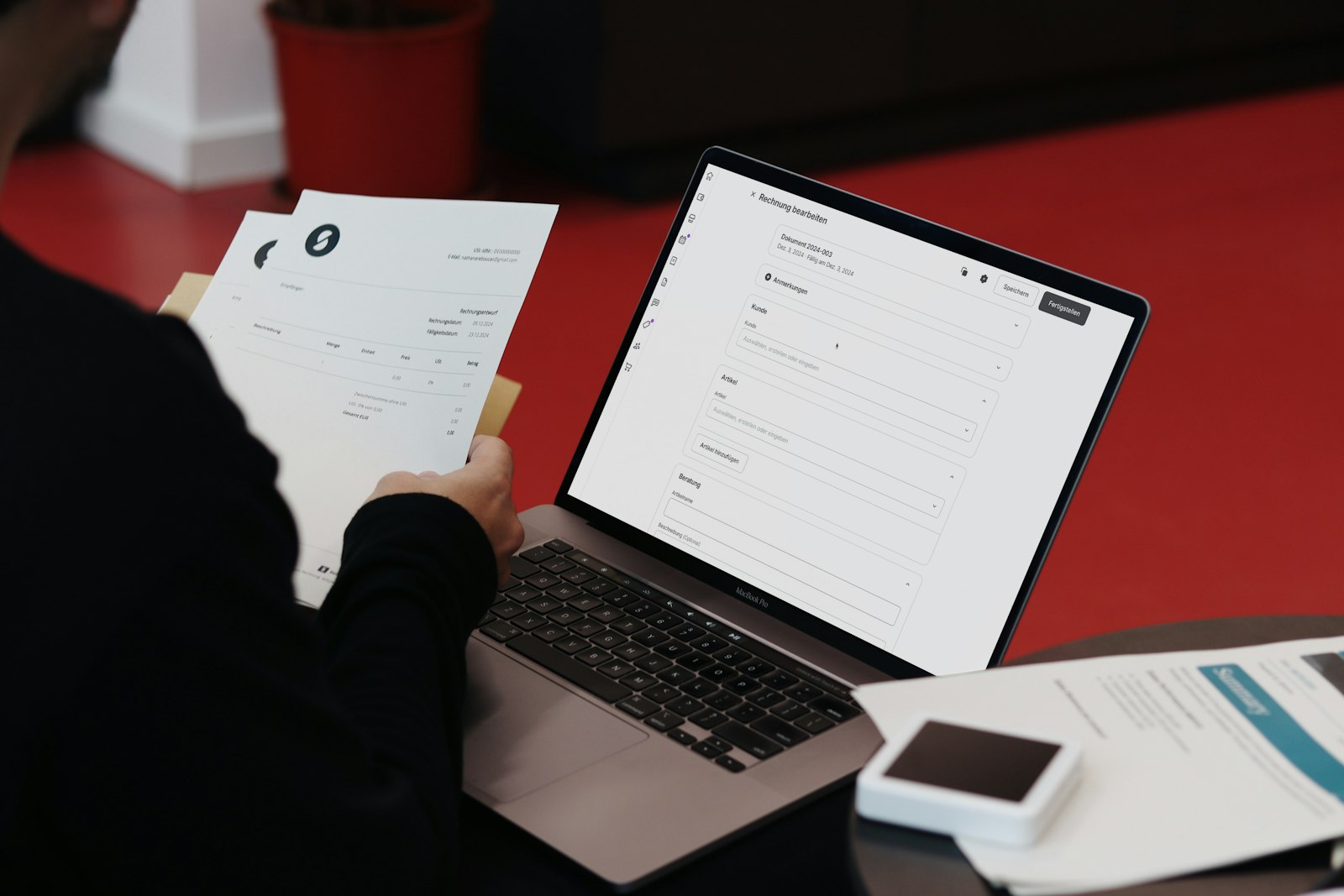 Personne à son bureau avec un ordinateur portable et des factures